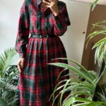 Person wearing a red and green plaid long sleeve midi dress with black belt.