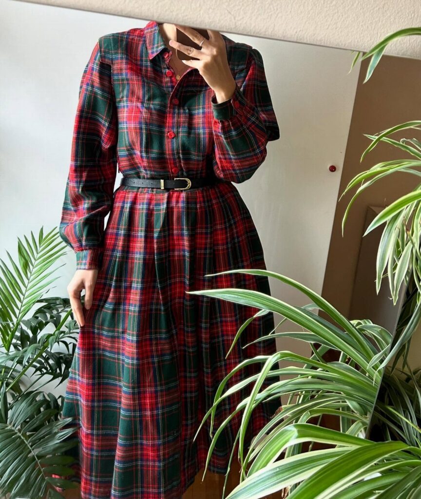Person wearing a red and green plaid long sleeve midi dress with black belt.