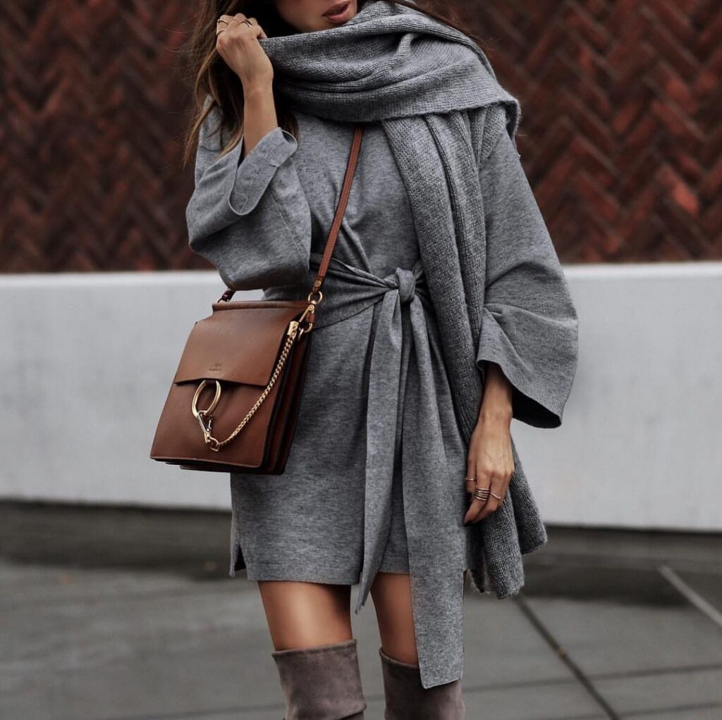 Woman wearing a grey sweater dress, large scarf, and grey over-the-knee boots.