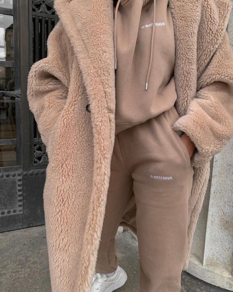 Person wearing a long tan teddy bear coat with a matching tan hoodie and sweatpants.